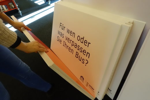 Stapel der Fragetafeln. Auf der Tafel steht "Für wen oder was verpassen Sie Ihren Bus?"