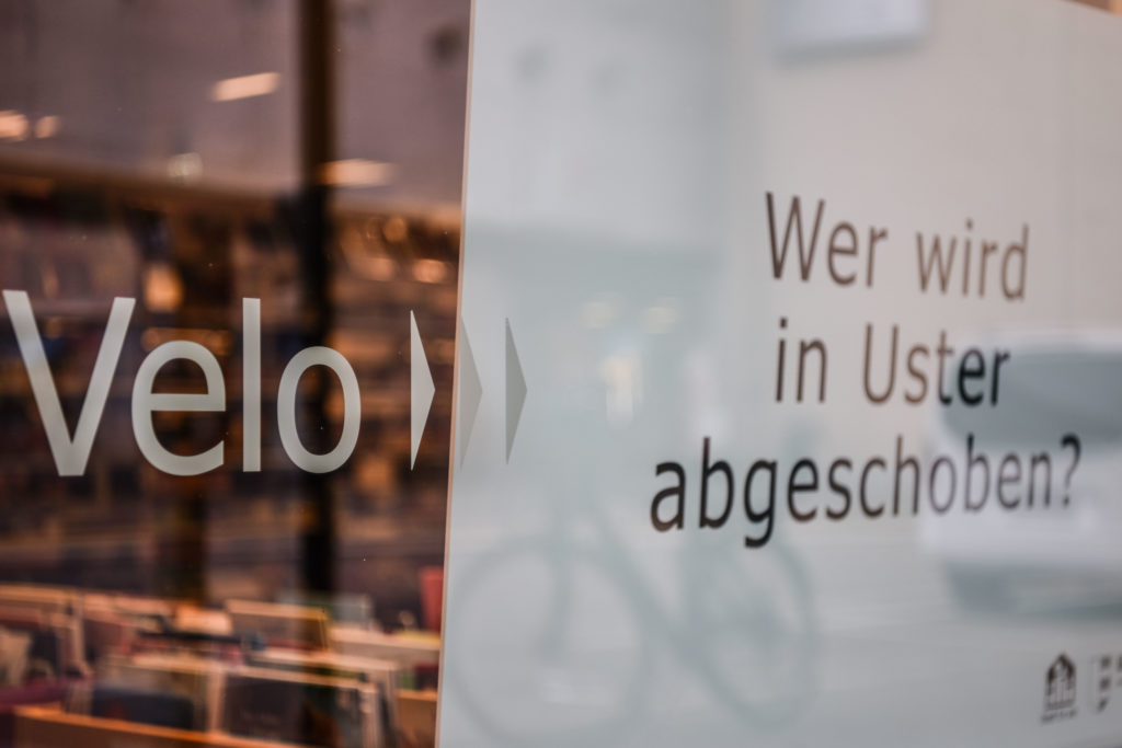 Das Schaufenster der Bibliothek. Es zeigt die Frage: "Wer wird in Uster abgeschoben?"