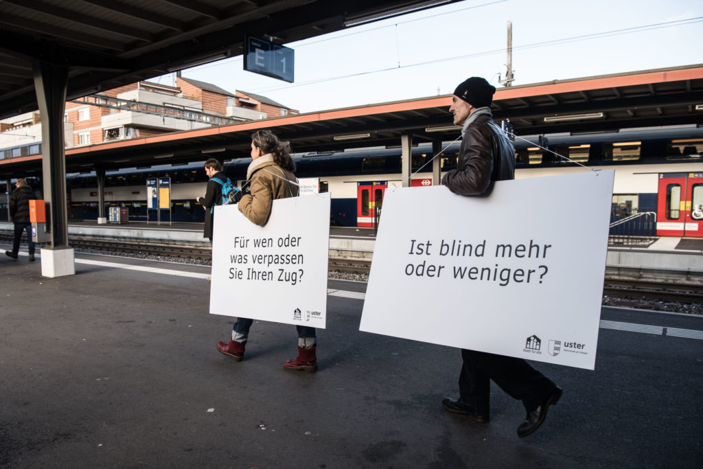 Ein Mann und eine Frau auf dem Perron mit Fragentafeln.