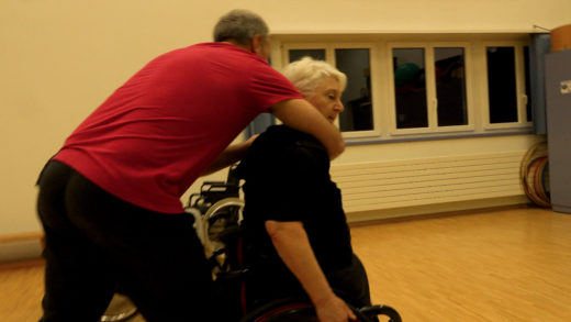 Eine Frau im Rollstuhl übt mit einem Trainingspartner die Selbstverteidigung