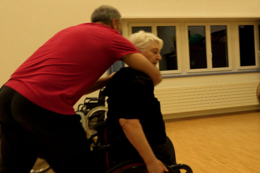 Eine Frau im Rollstuhl übt mit einem Trainingspartner die Selbstverteidigung