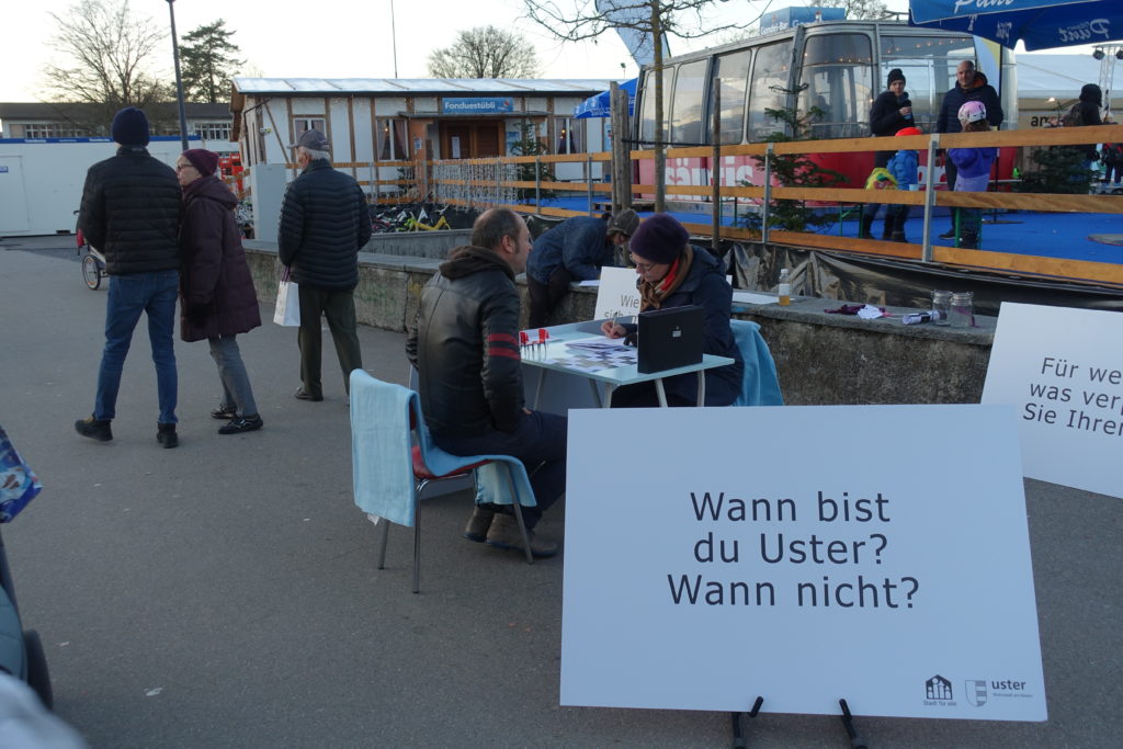 Am Tisch der Zuhörerei im Stadtpark sitzt ein Mann in Lederjacke und unterhält sich mit der Frau gegenüber am Tisch.