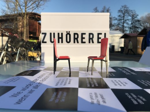 Zwei kleine rote Stühle, die die Zuhörerei symbolisieren.