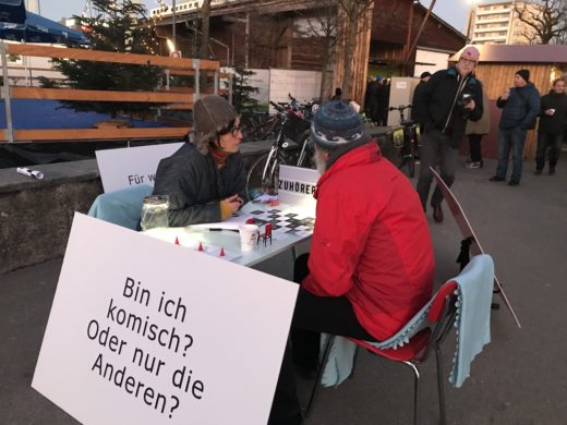 Ein Mann in roter Jacke ist am Tisch der Zuhörerei im Gespräch mit Lena Estermann.