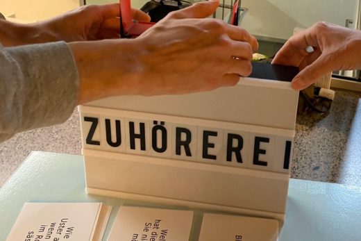 Eine Box auf dem Tisch zeigt das Wort Zuhörerei in grosser Schrift.