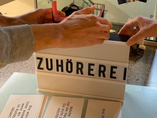 Eine Box auf dem Tisch zeigt das Wort Zuhörerei in grosser Schrift.