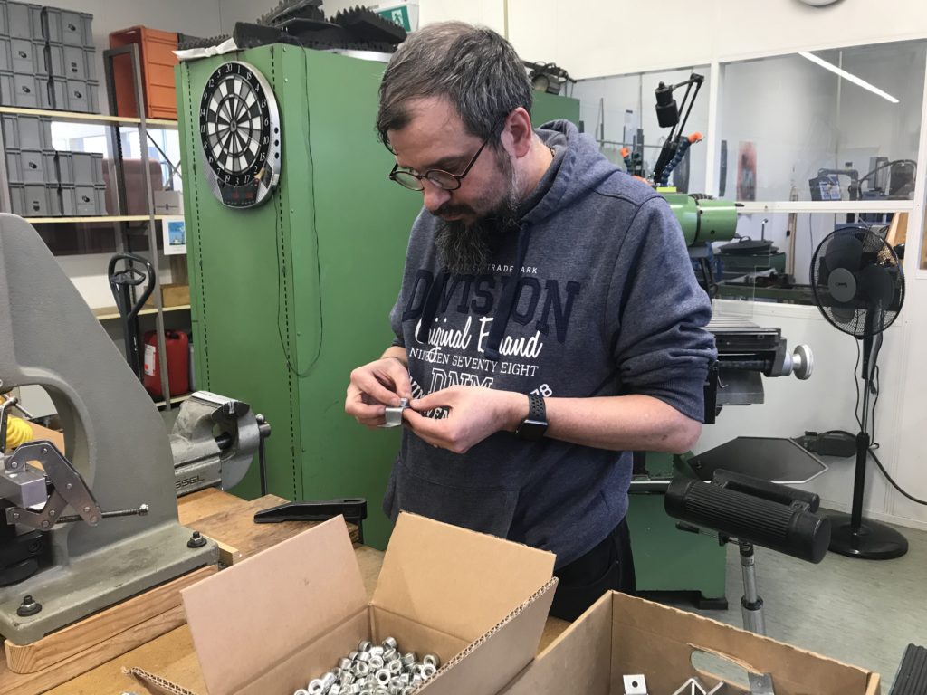 Mann bei der Arbeit im Produktwerk vom Werkheim. Er schraubt zwei Teile zusammen.