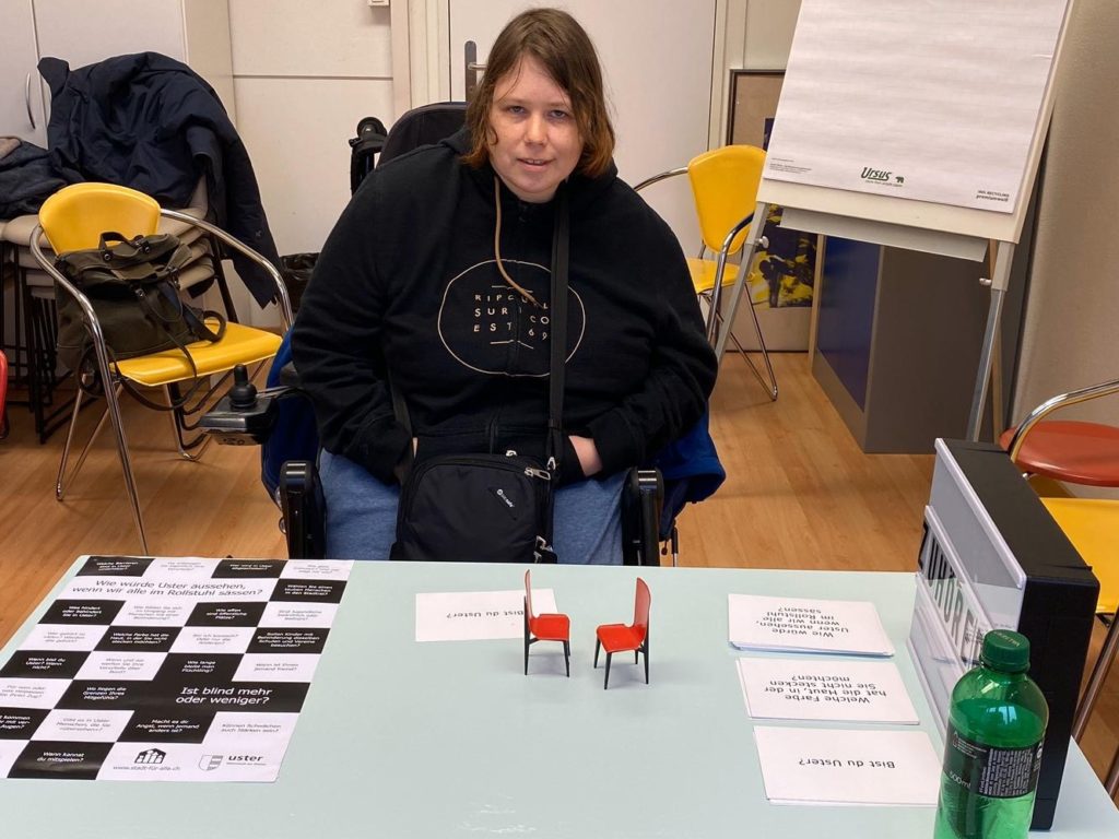 Junge FRau im Rollstuhl sitzt am Tisch der Zuhörerei im Produktwerk des Werkheims.