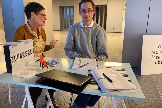 Beatrice Stebler befragt Linus Hut. Die beiden sitzen am TIsch nebeneinander.