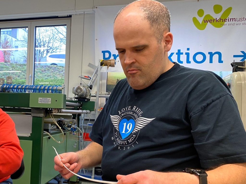 Ein Mann kontrolliert ein ausgedrucktes Schild. Der Mann arbeitet in der Arbeitsstätte vom Werkheim Uster