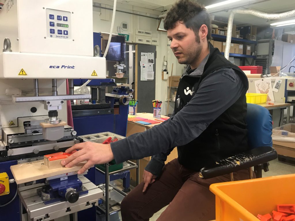 Junger Mann sitzt an einer Druckmaschine im Produktwerk vom Werkheim