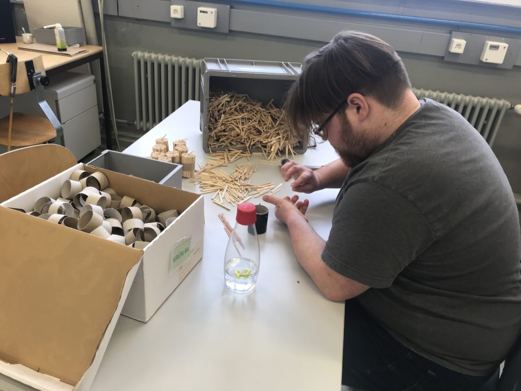 Ein junger Mann an seinem Arbeitsplatz im Produktwerk vom Werkheim. Er produziert Klumets, eine Anfeuerhilfe