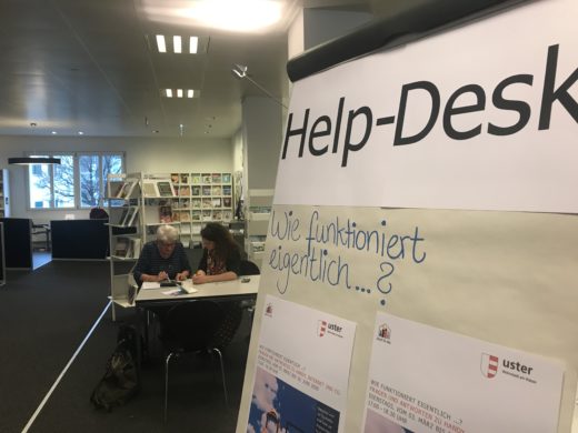 Auf einer grossen Tafel in der Bibliothek steht"Wie funktioniert eigentlich?" In grosser Schrift Help-Desk.