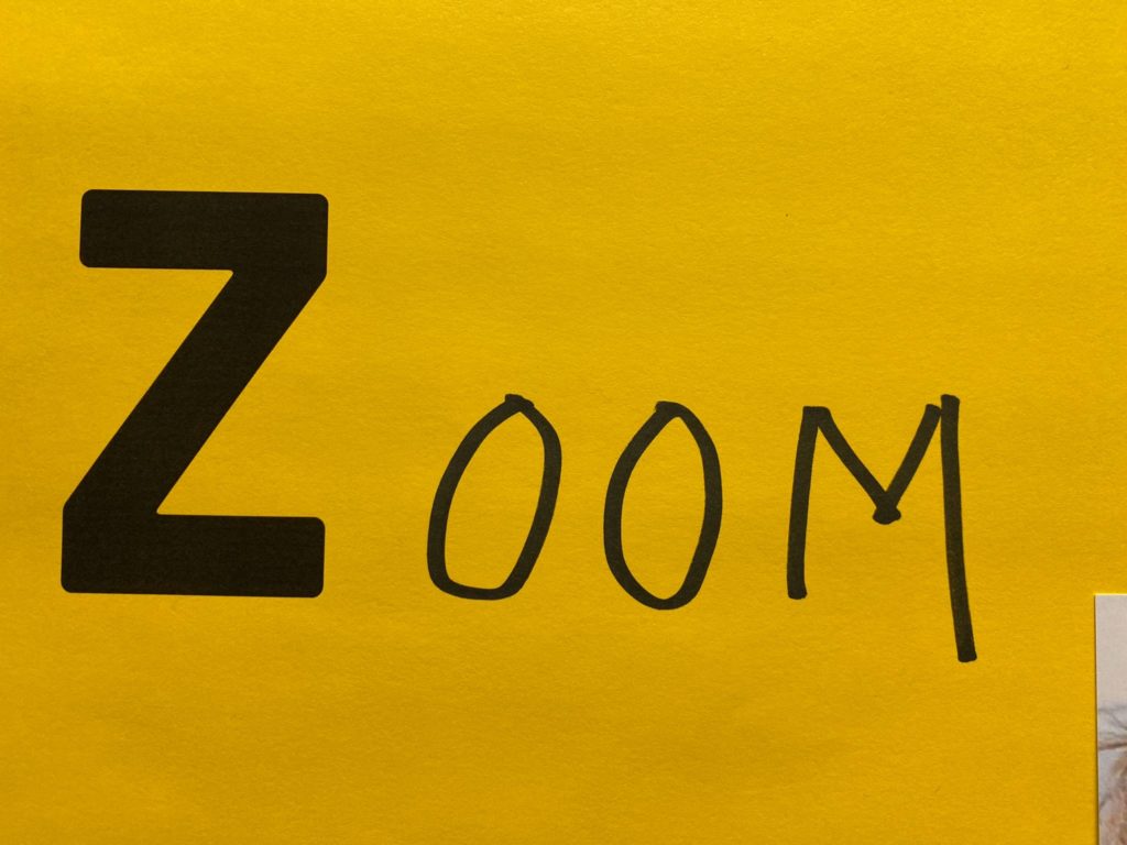 Das Bild zeigt den Schriftzug Zoom auf gelbem Hintergrund. Zoom ist eine Online-Plattform für Schulungen, Konferenzen, Meetings
