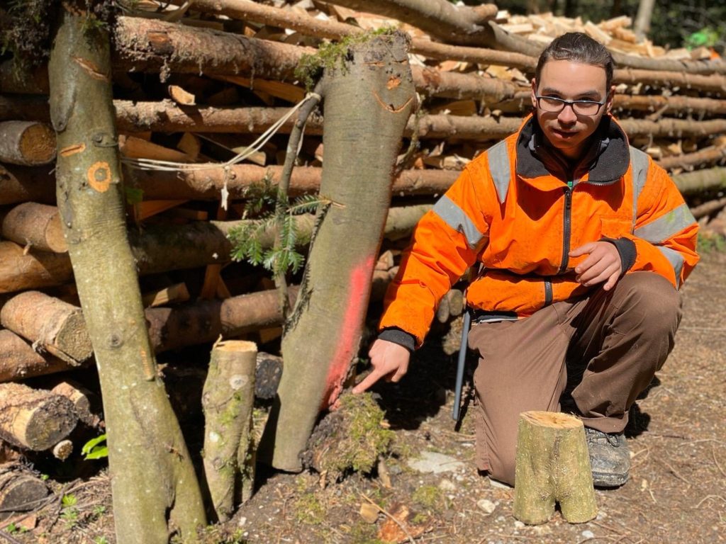 Junger Werkheimbewohner kniet im Wald auf dem Boden.
