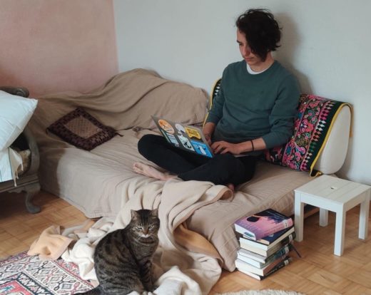 Ein junger Mann sitzt mit seinem Laptop auf seinem Bett im Homeoffice.