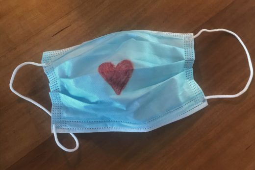 Papiermaske mit einem aufgemalten roten Herz