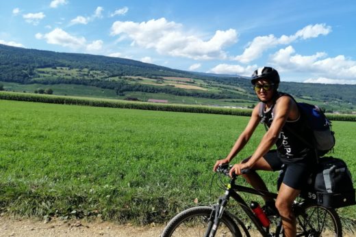 Junger Mann fährt mit dem Fahrrad durch grüneLandschaft.