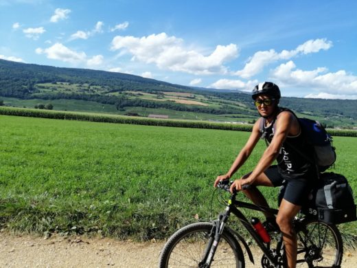 Junger Mann fährt mit dem Fahrrad durch grüneLandschaft.