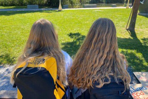 Zwei junge Frauen sitzen im Stadtpark. Man sieht sie von hinten. Es sind die beiden Gesprächspartnerinnen im Blog-Text.