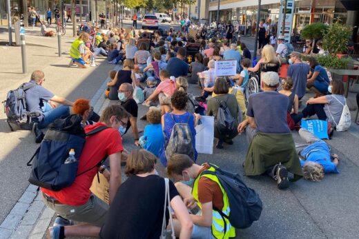 Klimademonstranten sitzen auf dem Strassenboden vor der Migros in Uster.