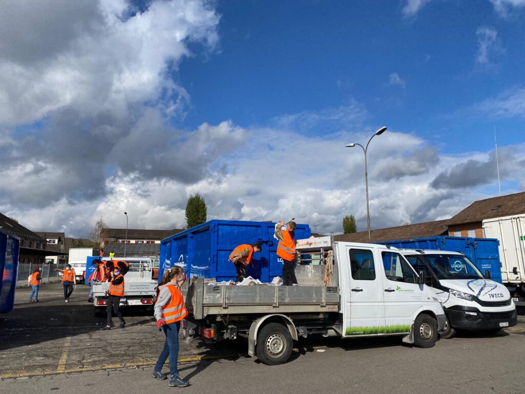 Jugendliche entladen einen Lastwagen mit Zeitungspapier und werden dieses in Mulden.