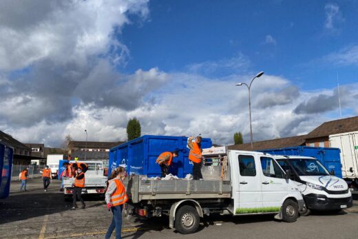 Jugendliche entladen einen Lastwagen mit Zeitungspapier und werden dieses in Mulden.