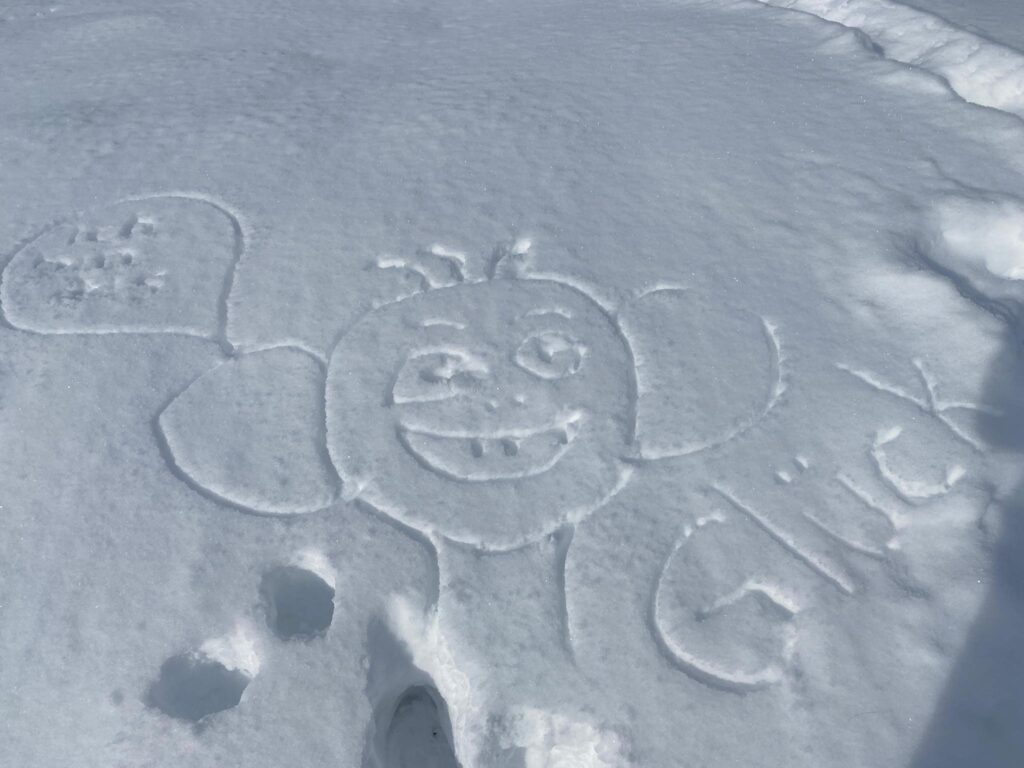 Weisser Schee. Darin gezeichnet ein lustiges Gesicht. Daneben steht das Wort: Glück.