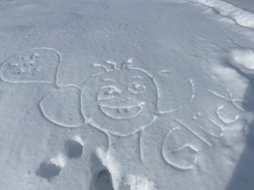Weisser Schee. Darin gezeichnet ein lustiges Gesicht. Daneben steht das Wort: Glück.