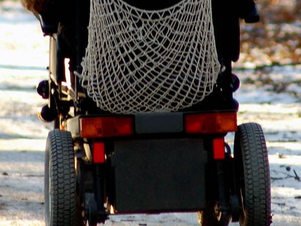 Rückenansicht von einem rer*in ist nicht zu erkennen.renden Rollstuhl. Fah